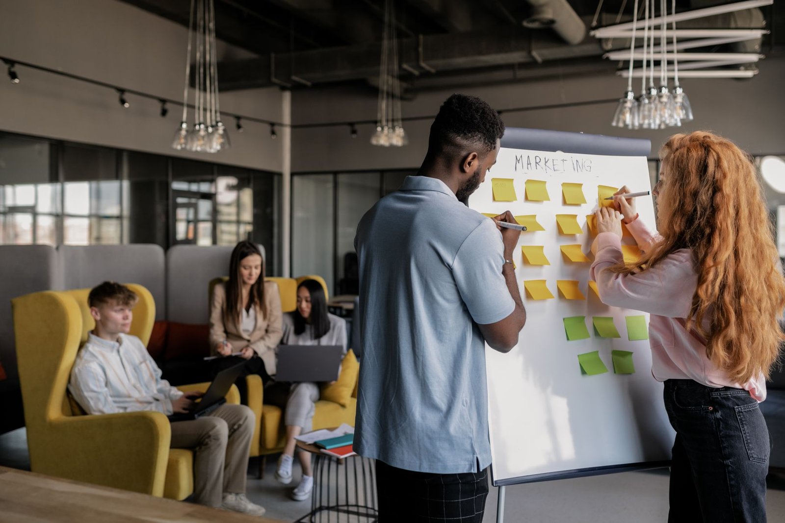A small marketing team planning a campaign on a whiteboard in an open-plan office
