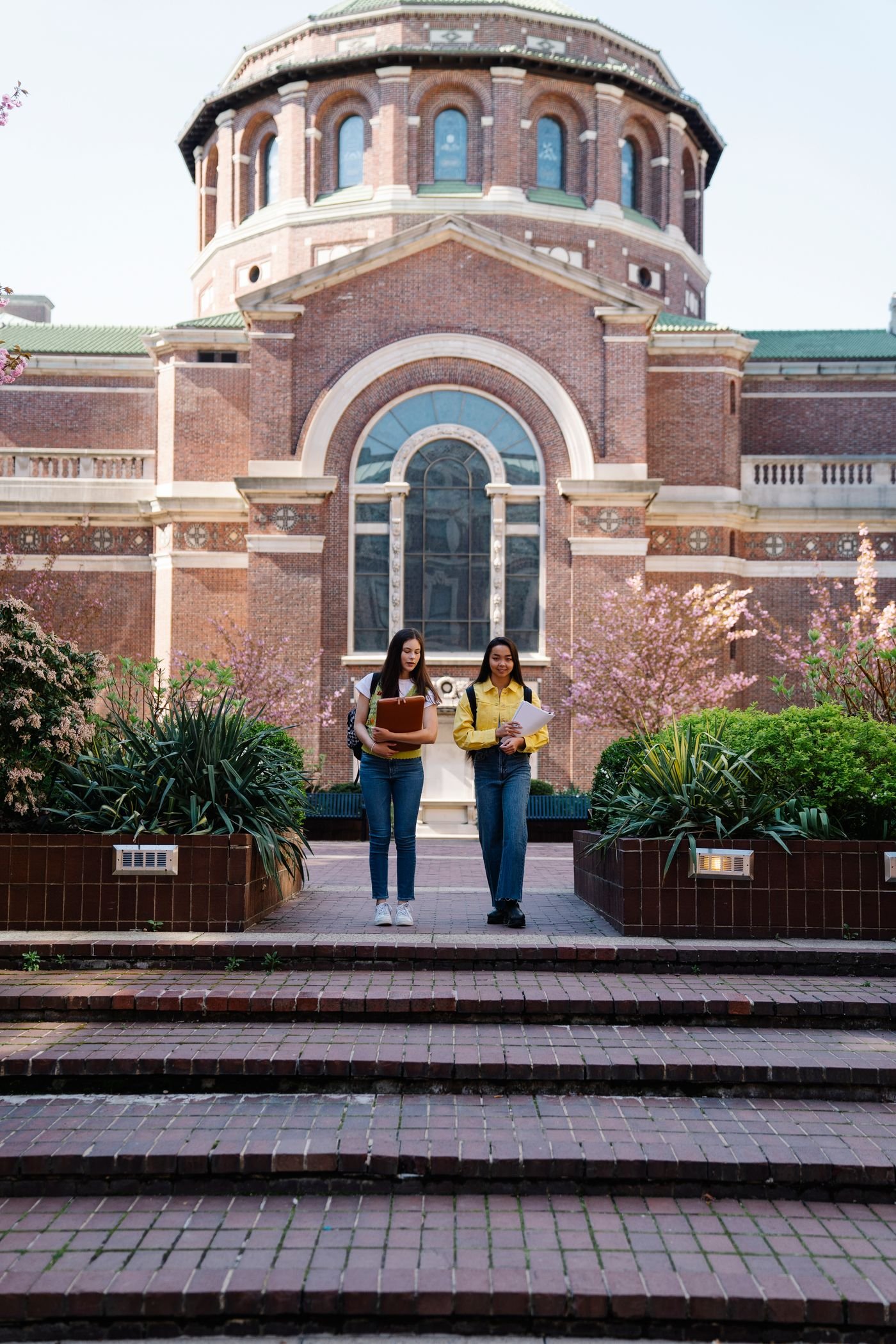 Two students walking down the steps of a university building in spring