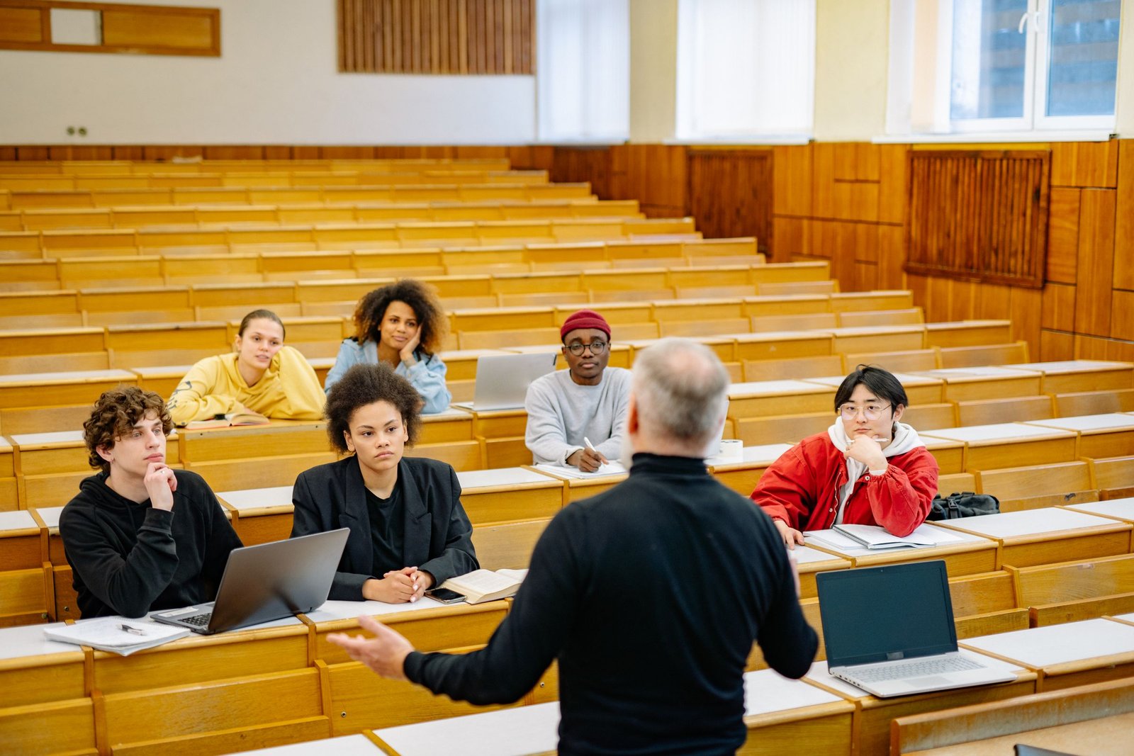 A large tiered lecture theatre with only a handful of students seated, listening to a lecturer